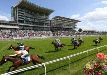 Horse race in progress with spectators watching from a multi-tiered stadium